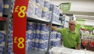 An employee stocks toilet paper along an aisle of an Asda store in Kendal, northwest England, Britain August 30, 2015. Reuters/Suzanne Plunkett