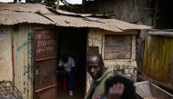 Residents of Kibera slum in Kenya's capital Nairobi sit outside a makeshift soda depot on September 26, 2019 with a notification inscribed on the door to clients that payments in the old tender notes are no longer accepted. AFP / Tony Karumba 