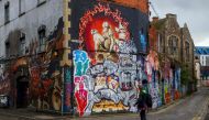 A pedestrian walks past graffiti street art on the side of a building in Bristol on May 8, 2019. AFP / Geoff Caddick