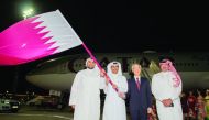 Jassim bin Rashid Al Buenain, Secretary-General of the Qatar Olympic Committee, holding the national flag with officials at the Hamad International Airport yesterday, before hanging the same to a Qatar Airways pilot to be flown to Tokyo where the 2020 Sum