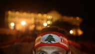 A Lebanese anti-corruption protester, his forehead wrapped with the national flag, poses in front of the Grand Serail (government building) during a protest in downtown Beirut on December 22, 2019.  AFP / PATRICK BAZ