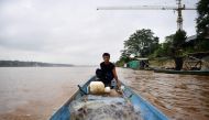 Fisherman Kome Wilai fishing from his boat along the Mekong River between Chiang Rai province in Thailand (R) and Laos (L) on September 20, 2019. AFP / Lillian Suwanrumpha