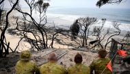 Soldiers sit on a beach amongst burnt trees where people had previously taken shelter during a fire on New Year's Eve in Mallacoota, Australia January 10, 2020. Reuters/Tracey Nearmy
 