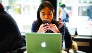A woman uses her Apple iPhone and laptop in a cafe in lower Manhattan in New York City, US, May 8, 2019. Reuters/Mike Segar
