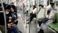 Passengers wearing protective face masks travel on the subway in Shanghai on February 25, 2020. China on February 25 reported another 71 deaths from the COVID-19 coronavirus, the lowest daily number of fatalities in over two weeks, which raised the toll t