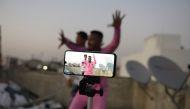 In this file photo taken on February 14, 2020 youths act in front of a mobile phone camera while making a TikTok video on the terrace of their residence in Hyderabad. This is TikTok's time./ AFP / NOAH SEELAM