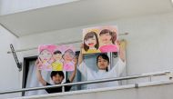 Reku Matsui, 8, and Yaya Matsui, 12, pose for a photograph while holding pictures that they drew during the coronavirus disease (COVID-19) outbreak, as they stand on the balcony of their home in Tokyo, Japan, April 19, 2020. REUTERS/Kim Kyung-Hoon 