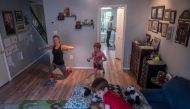 Mimicked by her son Daniel (R), Paulina Mansz, a group fitness instructor, records a workout session for her clients while her other son Javier relaxes and her husband Manuel cooks in the kitchen, as she continues to instruct from home in Arlington, Virgi