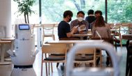 Customers wait at a cafe where a robot that takes orders, makes coffee and brings the drinks straight to customers is being used in Daejeon, South Korea, May 25, 2020. REUTERS/Kim Hong-Ji