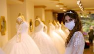 An employee presents a wedding dress with a mask at the Mezopotamya bridal gowns shop, amid the spread of the coronavirus disease (COVID-19), in Diyarbakir, Turkey, June 29, 2020. Picture taken June 29, 2020. REUTERS/Sertac Kayar