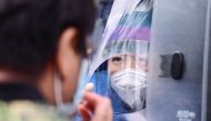 A health worker carries out a COVID-19 coronavirus test on a resident in a testing vehicle in Shenyang in China's northeastern Liaoning province on July 29, 2020. China OUT / AFP / STR