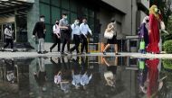 People wearing protective masks are reflected in a water puddle as they cross a street, amid the coronavirus disease (COVID-19) outbreak in Kuala Lumpur, Malaysia October 2, 2020. REUTERS/Lim Huey Teng
