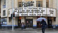 Passers-by shelter under umbrellas outside a Picturehouse cinema in west London on October 4, 2020. Cineworld, which own the Picturehouse chain of cinemas, is set to close its 128 UK sites in the coming weeks. / AFP / JUSTIN TALLIS