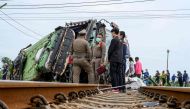 Investigators work by the wreckage of an overturned bus involved in a deadly collision with a train next to Khlong Kwaeng Klan railway station in Chachoengsao province, east of the Thai capital Bangkok, on October 11, 2020. / AFP / Mladen ANTONOV