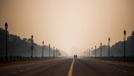People walk along Rajpath street during a smoggy morning in New Delhi on October 15, 2020. / AFP / Jewel SAMAD
