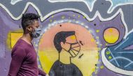 A man wearing a face mask walks past an advocacy graffiti urging for mask wearing amid the COVID-19 coronavirus pandemic in Addis Ababa, Ethiopia on October 26, 2020. / AFP / AMANUEL SILESHI