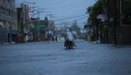 A resident cycles along a flooded street due to heavy rains brought by Super Typhoon Goni in Legazpi City, Philippines' Abay province on November 1, 2020. / AFP / Charism SAYAT