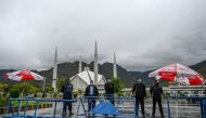 FILE PHOTO: Policemen wearing facemasks stand guard at a checkpoint beside the Grand Faisal Mosque during a government-imposed nationwide lockdown as a preventive measure against the COVID-19 coronavirus, in Islamabad on March 27, 2020. / AFP / Aamir QURE