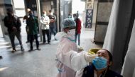A medical worker collects a swab sample for a Rapid Antigen Test (RAT) for the Covid-19 coronavirus from a passenger before boarding a train at Hazrat Nizamuddin Railway Station in New Delhi on November 10, 2020. / AFP / XAVIER GALIANA