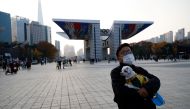 A man holding a pet dog takes a walk amid the coronavirus disease (COVID-19) pandemic at a park in Seoul, South Korea, November 13, 2020. REUTERS/Kim Hong-Ji