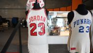 In this file photo taken on November 23, 2020, a Michael Jordan 1984 signing day Chicago Bulls official NBA game jersey is displayed beside US President Barack Obama's 1978-1979 game worn high school basketball jersey from Hawaii's Punahou School at a med