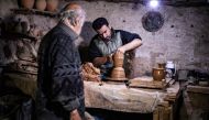Syrian-Armenian potter Misak Antranik Petros watches his son Anto moulding a clay vase at his workshop located inside an ancient mud-brick house near the city of Qamishli in Syria's northeastern Hasakeh province, on December 19, 2020. AFP / Delil Souleima