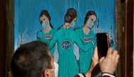 A man records a video of a painting representing Moderna, Pfizer and AstraZeneca vaccines at Bisbe street, during the coronavirus disease (COVID-19) outbreak, in Barcelona, Spain, January 27, 2021. REUTERS/ Albert Gea 