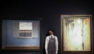 A gallery assistant stands next to artwork titled 'Le Mois des Vendanges' by Rene Magritte and 'Peinture' by Joan Miro, during a photocall at Christie's auction house, in London, Britain, March 16, 2021. The items are to go on sale at the forthcoming 20th