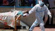 A health worker wearing personal protective equipment (PPE) carries a patient suffering from the coronavirus disease (COVID-19) outside the casualty ward at Guru Teg Bahadur hospital, in New Delhi, India, April 24, 2021. REUTERS/Adnan Abidi TPX IMAGES OF 
