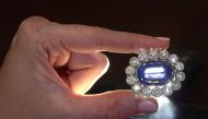 A staff holds a sapphire and diamond brooch part of a nine pieces parure of sapphires and diamonds, owned by Napoleon?s adopted daughter Stephanie de Beauharnais, displayed 200 years after the Emperor's death, during a preview at Christie?s before their M
