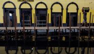 A man carries a box with oranges as he walks over wooden walkways installed by the city hall over a street flooded by waters from the Negro river in downtown of Manaus, in Amazonas State, Brazil May 17, 2021. REUTERS/Bruno Kelly