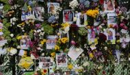 Photos and flowers hang in a fence at a memorial site created by neighbors in front of a partially collapsed residential building as the emergency crews continue search and rescue operations for survivors, in Surfside, near Miami Beach, Florida, U.S. June