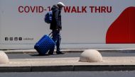 A man wearing a face mask pushes his luggage next to a Unilabs container where health technicians perform COVID-19 antigen tests for tourists and citizens in Lisbon, Portugal, July 29, 2021. REUTERS/Nacho Doce