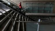 A person in a face mask rides an escalator in an otherwise empty pedestrian mall during the outbreak of the coronavirus disease (COVID-19) in the Downtown area of Manhattan, New York City, U.S., August 9, 2021. REUTERS/Andrew Kelly