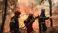 Two firefighters from Greece and one firefighter from Slovakia try to extinguish a wildfire burning in the village of Avgaria, on the island of Evia, Greece, August 10, 2021. REUTERS/Stelios Misinas