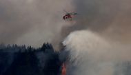 A firefighting helicopter makes a water drop as a wildfire burns in the village of Galatsona, on the island of Evia, Greece, August 10, 2021. REUTERS/Nicolas Economou