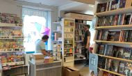 A man looks at items as a staff member works at a local bookstore in east-coast small-town Trosa, Sweden August 11, 2021. REUTERS/Anna Ringstrom