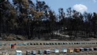 Beehives are seen in front of burnt trees, following a wildfire near the village of Rovies on the island of Evia, Greece, August 12, 2021. REUTERS/Stelios Misinas