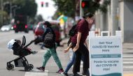 People walk past a sign for a coronavirus disease (COVID-19) vaccination clinic in Los Angeles, California, U.S., August 17, 2021. REUTERS/Lucy Nicholson

