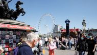 People wearing protective masks walk on Westminster Bridge, with the London Eye in the background, in London, Britain, June 1, 2021. REUTERS/John Sibley/File Photo
