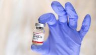 A woman holds a small bottle labelled with a 