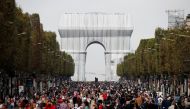 People walk near the Arc de Triomphe monument, fully wrapped as part of an art installation entitled 