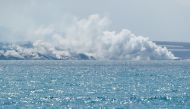 Lava flows and smoke rises, as seen from Tazacorte Port, following the eruption of a volcano on the Canary Island of La Palma, Spain, September 30, 2021. REUTERS/Borja Suarez