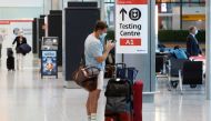 A passenger stands next to a COVID-19 testing centre sign in the International arrivals area of Terminal 5 in London's Heathrow Airport, Britain. (REUTERS/Peter Nicholls/File Photo)