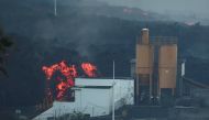 Lava rolls down behind a cement factory in Los Llanos as the Cumbre Vieja volcano continues to erupt on the Canary Island of LA PALMA, as seen from Tajuya, Spain, October 11, 2021. REUTERS/Sergio Perez
