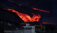 Lava flows down behind houses in Los Llanos as the Cumbre Vieja volcano continues to erupt on the Canary Island of La Palma, as seen from Tajuya, Spain, October 13, 2021. REUTERS/Sergio Perez