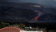 Two people look at lava spewed from the Cumbre Vieja volcano from a house nearby as it continues to erupt on the Canary Island of La Palma, as seen from Tajuya, Spain, October 20, 2021. Reuters/Susana Vera