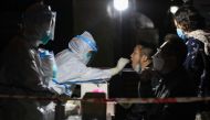 A medical worker in protective suit collects a swab from a resident at a makeshift nucleic acid testing site inside a residential compound, following new cases of the coronavirus disease (COVID-19), in Zunyi, Guizhou province, China October 21, 2021. Pict