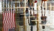 A U.S. flag is reflected on the floor as passengers make their way through Reagan National Airport in Washington, U.S., July 1, 2016. REUTERS/Kevin Lamarque/File Photo