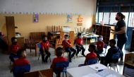 A teacher talks to children in the classroom about bio-safety rules, on the first day back to in-person instruction after it was suspended due to the coronavirus disease (COVID-19), in Caracas, Venezuela October 25, 2021. REUTERS/Leonardo Fernandez Vilori